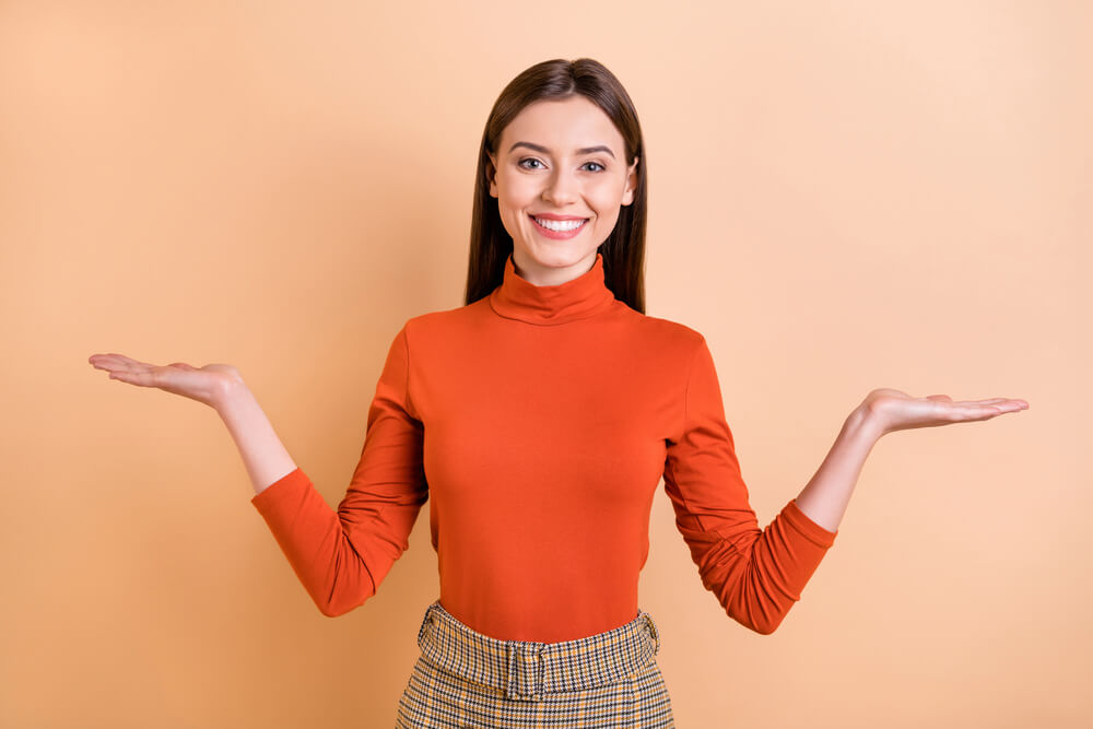 Femme en orange présente les mains ouvertes